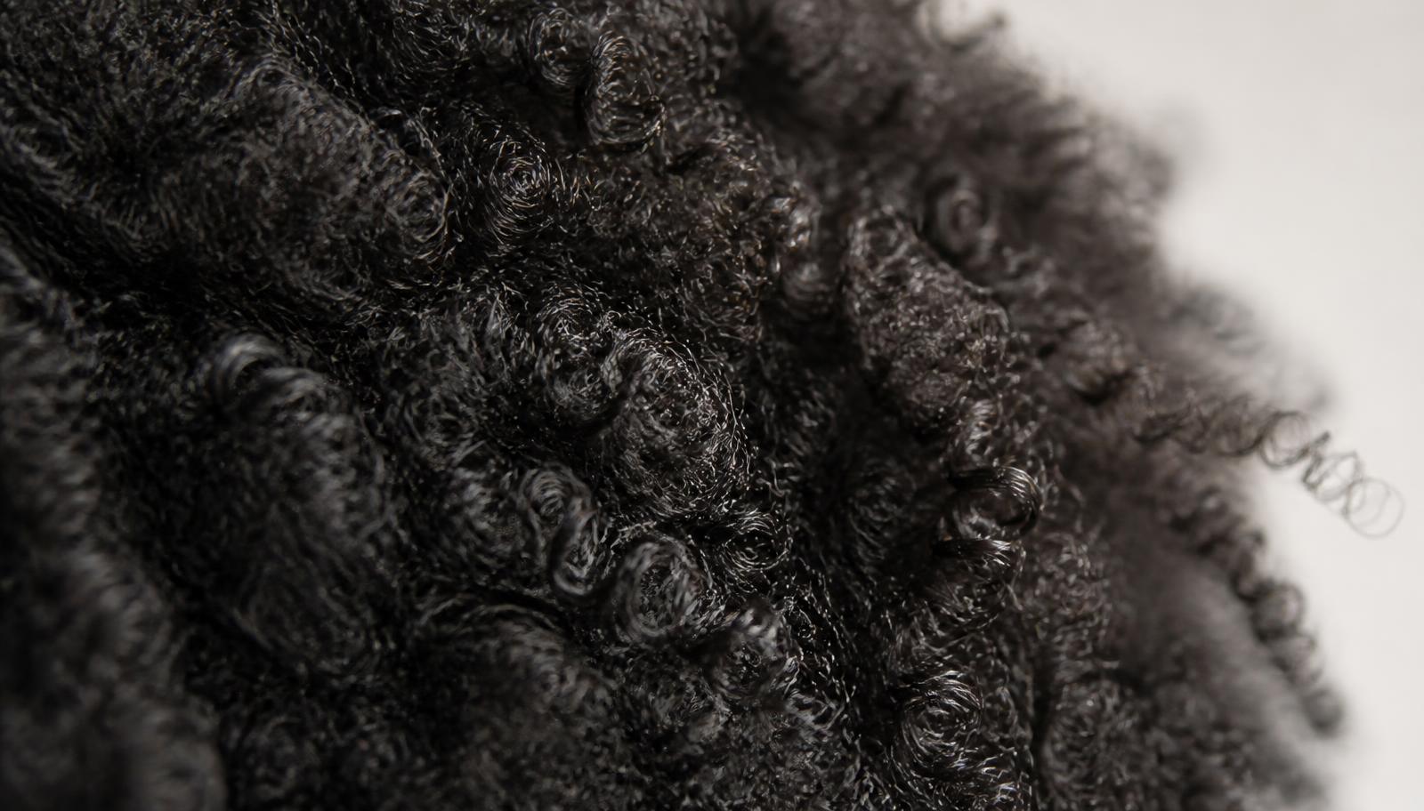 Professional assessing tightly coiled afro hair before a Nanoplastia service